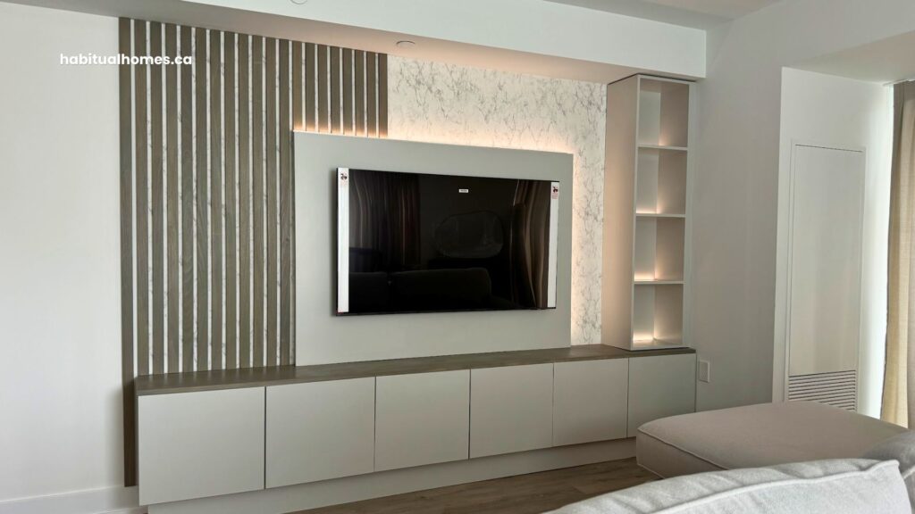 Custom media wall with custom-stained poplar slats and integrated lighting in a Bloor East Toronto condo living room with white sofa