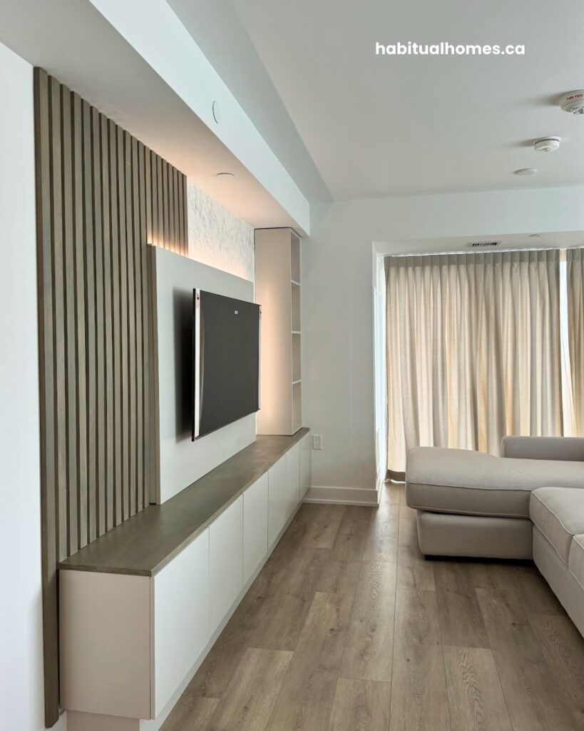 Detail of custom built-in storage column with vertical poplar slats and LED-lit shelves on a Bloor East Toronto media wall
